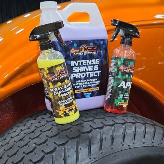 3 Speed And Shine bottles displayed on top of a black truck tire in front of an orange car