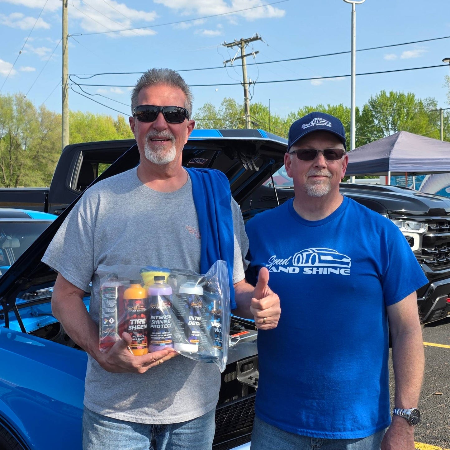 Two men standing in front of a blue truck holding a bag containing the Big 5 Bundle