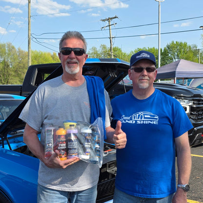 Two men standing in front of a blue truck holding a bag containing the Big 5 Bundle