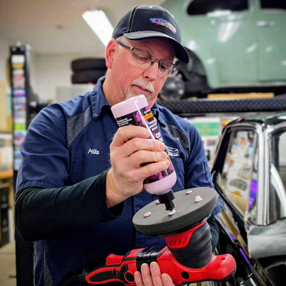 A man applies Correct & Enhance AIO onto a black rotary polisher attachment
