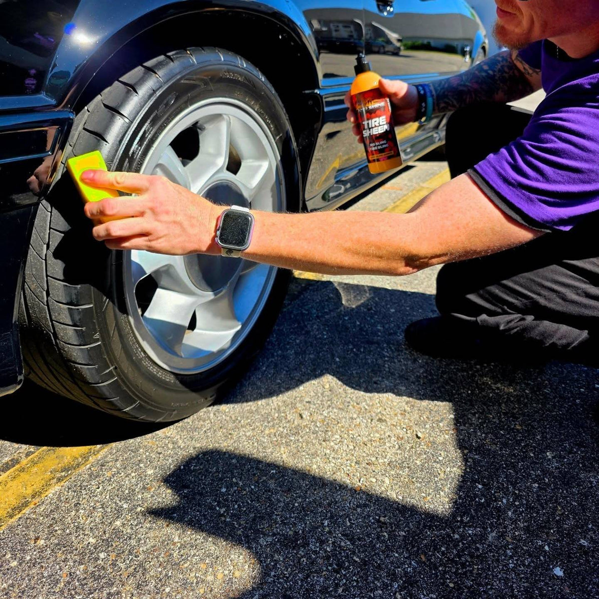 A person outdoors applies Speed And Shine Tire Sheen to a car tire