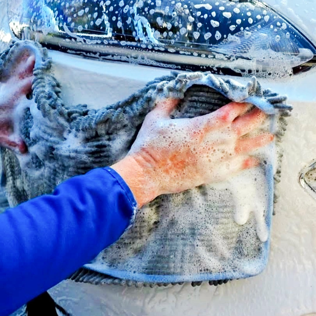 A person's soapy hand scrubbing with a microfiber mitt and Speed And Shine Vehicle Wash